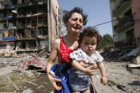 A Georgian woman holding her baby cries at her damaged home in Gori